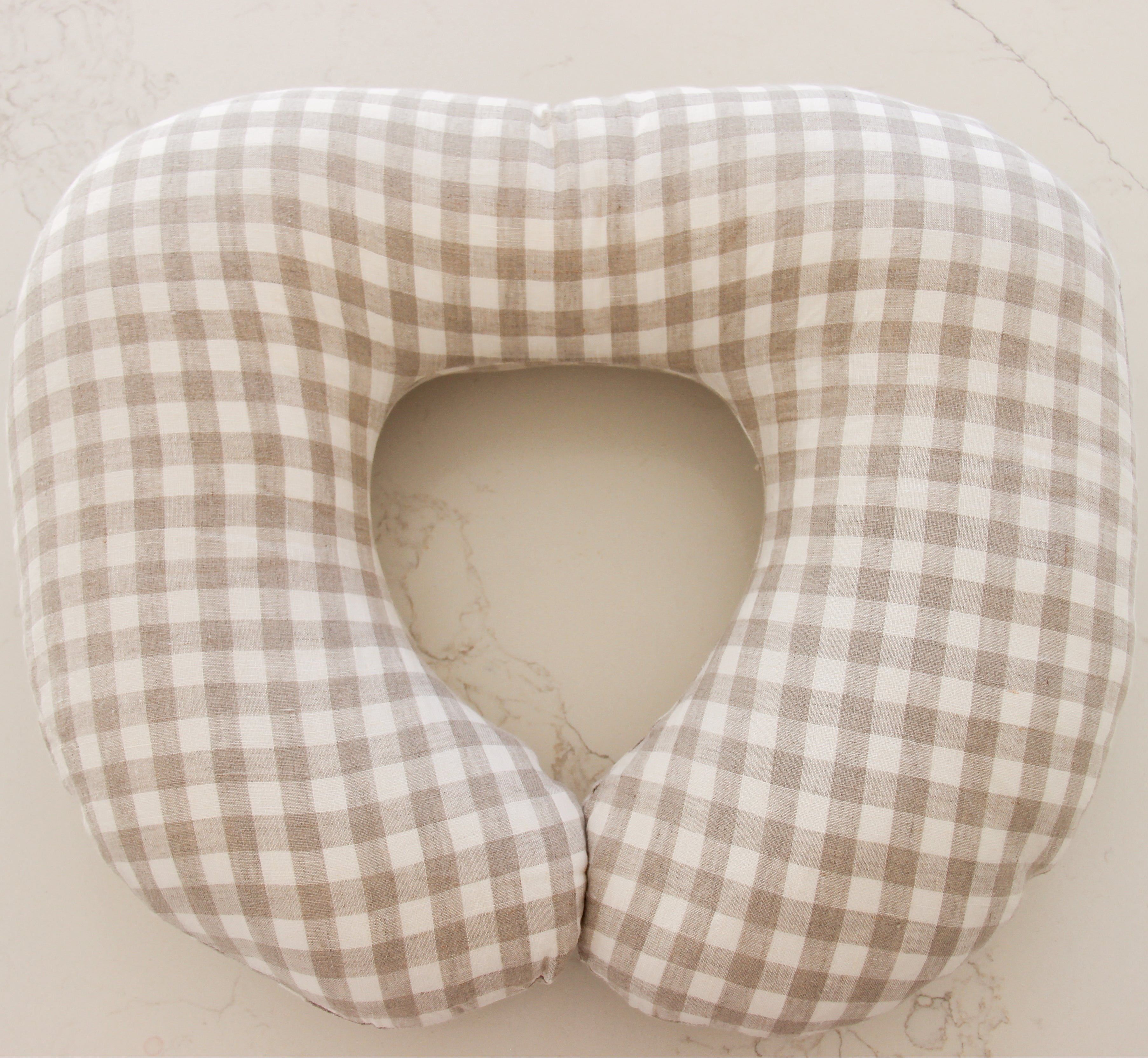 Plaid patterned nursing pillow on a light beige background