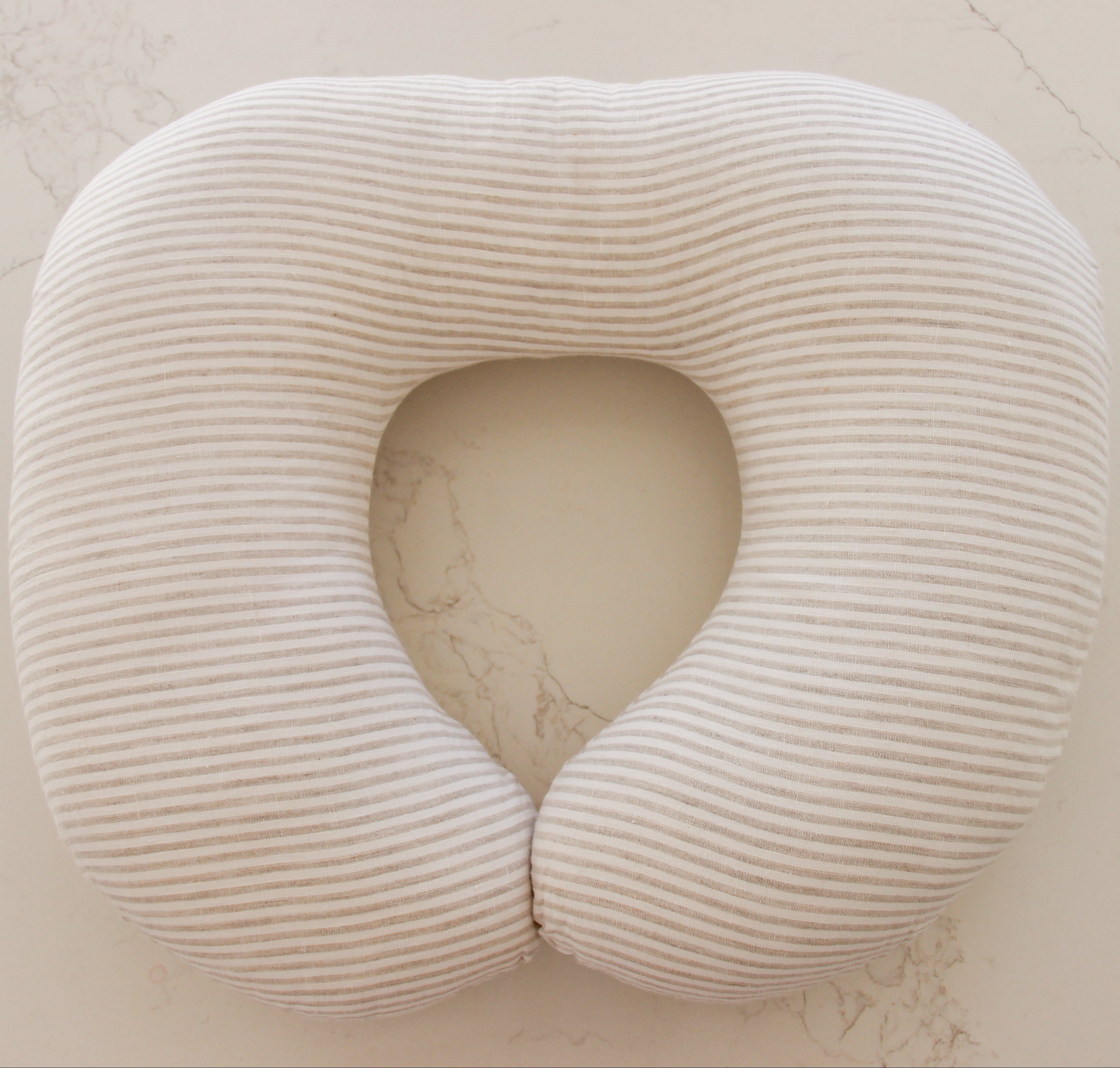 Beige ribbed nursing pillow on a light beige surface